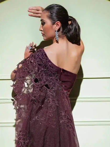 A model showcases a one-shoulder gown from "The Spotlight" collection, featuring a beautiful laser-cut and embroidered sleeve.