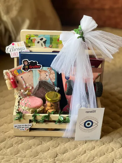This brother's Rakhi hamper includes a toy monster truck, snacks, and a personalized note, wrapped with a white tulle bow.