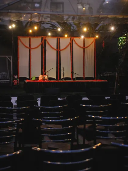 The stage, decorated with marigolds, awaits the artists. This simple, traditional touch adds to the authenticity and warmth of our Courtyard Baithak series.