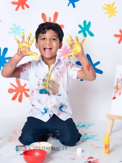 This boy is showing off his colorful, paint-covered hands with a huge, excited smile.