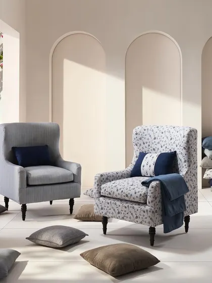 A light-filled, Mediterranean-inspired scene with two classic armchairs. The clean white space and arched doorways create a serene and airy backdrop for the floral and striped upholstery fabrics.