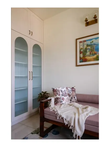 The study nook includes a sofa-bed and a storage unit with fluted glass arches, designed for an avid reader. The space is both functional and sophisticated.