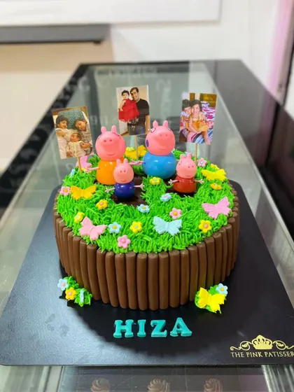 A lovely Peppa Pig garden cake. This design features a chocolate stick fence, green grass icing, and the Peppa Pig family enjoying a day out with photo memories.
