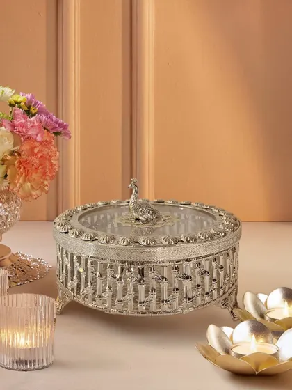 This silver-plated dry fruit box is a study in intricate detail. From the woven-style engraving to the regal peacock handle, it is a piece that is as beautiful to display as it is useful to serve from.