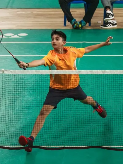 A junior player stretches for a backhand shot, demonstrating excellent technique. Our tournaments attract skilled young players, ensuring a high level of competition.