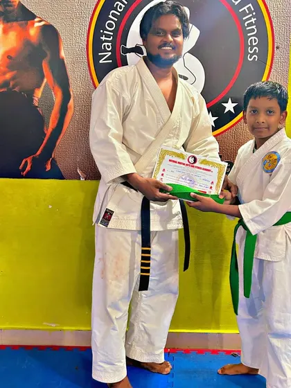 A student proudly receives his green belt, a mark of his progress in karate.