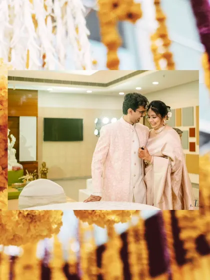 A creatively framed shot of the couple, seen through hanging marigold decorations, adding a touch of tradition to a modern portrait.