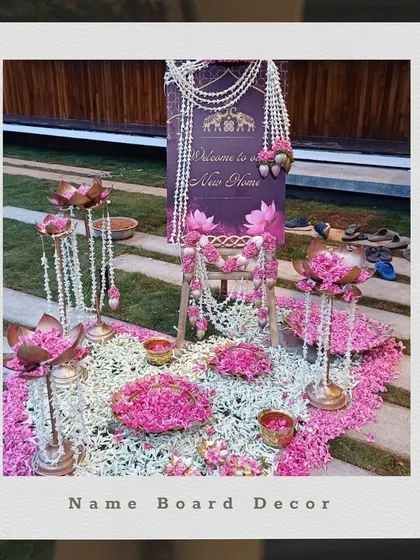 A beautiful name board decorated with lotus-shaped lamps and strings of pearls and flowers for a housewarming ceremony.