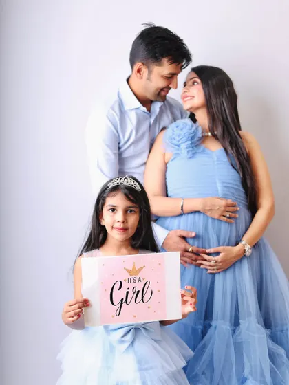 A beautiful maternity and family shoot announcing "It's a Girl." The older sister proudly holds the sign, sharing in the excitement of the growing family.