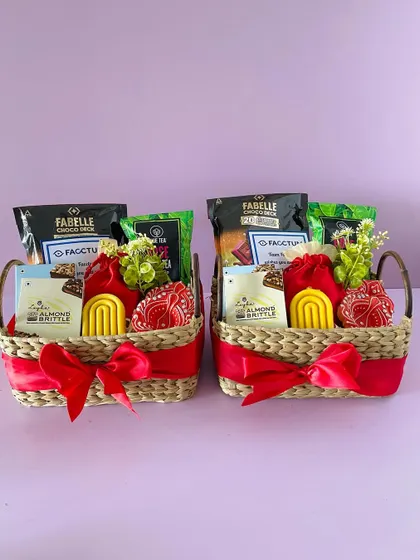 Two identical Kauna basket hampers, ready for a bulk order. The red ribbon and festive items make them perfect for Diwali.