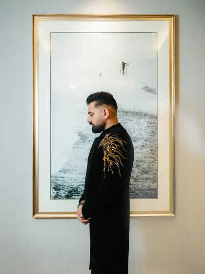 A stylish portrait of the groom before his big Sangeet performance. His embroidered black sherwani exudes elegance and confidence.