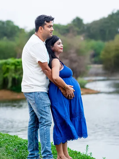 A peaceful moment captured by the water's edge. This pose beautifully showcases the baby bump and the couple's bond.