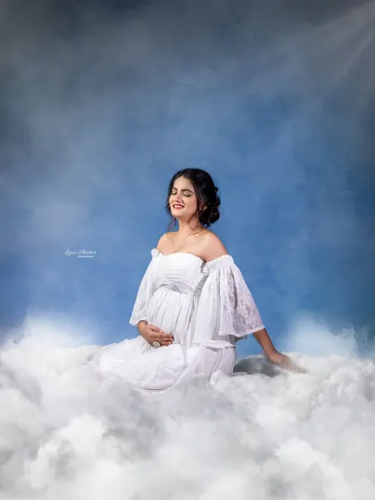 A moment of pure bliss. With eyes closed and a gentle smile, this mother-to-be looks completely serene, floating on a bed of clouds under a heavenly light.