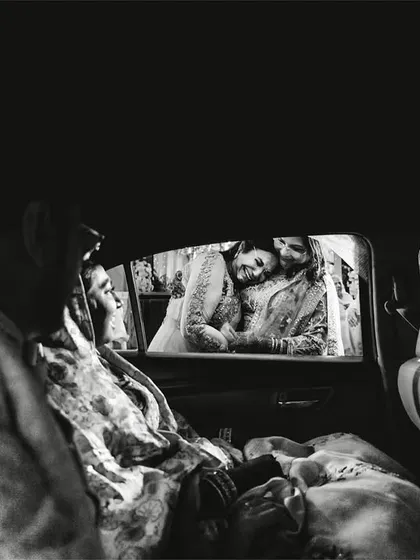 An emotional goodbye. This black and white shot from inside the car captures the poignant moment of the vidaai, a daughter's farewell to her family.