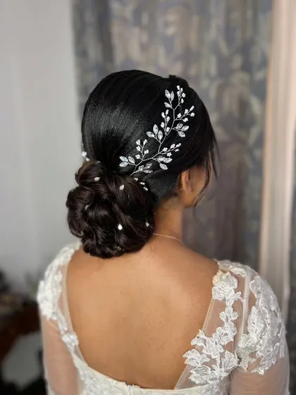 A side view of the bridal low bun, showing how the accessory gracefully sweeps across the hair. The scattered pearls add a final touch of delicate beauty.