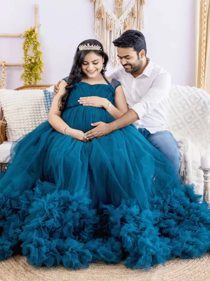 A joyful couple portrait in our bright studio. The mom-to-be is wearing a stunning blue ruffled gown and a crown, looking like a true queen.