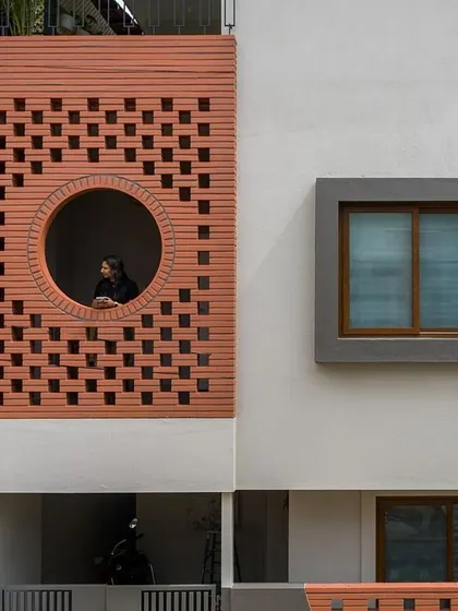 A portrait of our principal architect framed by the circular window of the terracotta jali facade, symbolizing our deep connection to biophilic design.