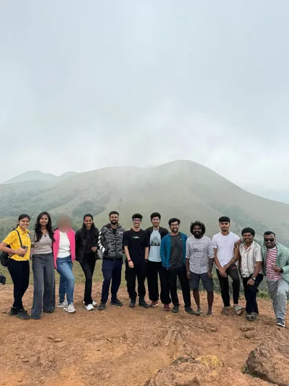 A group photo from a Coorg trip, with the rolling hills in the background.