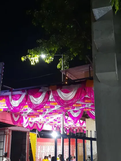 A beautifully decorated pandal ceiling with pink, white, and yellow drapes. This kind of ceiling work adds a grand, festive touch to any outdoor event.