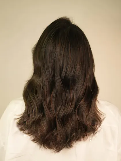 A beautiful example of cinnamon tones on mid-length hair, styled with soft waves to showcase the color's dimension.