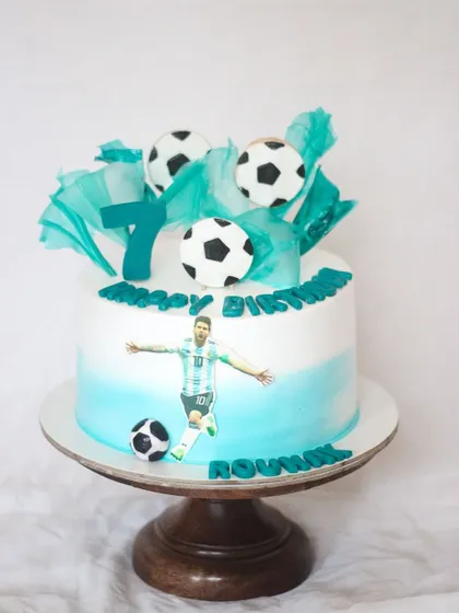 This cake was for a little football fan who was very specific with his requirements! It features his hero, Messi, along with edible soccer balls and rice paper sails in the team's colors.