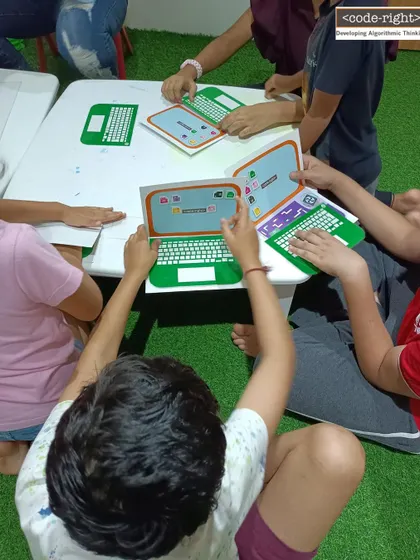 In this photo, you can see children working with my custom "paper laptops." This activity helps them understand the components of a computer and coding interfaces in a tangible, screen-free way, making abstract concepts more concrete.