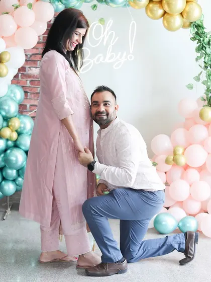 This is a sweet, candid moment between the parents-to-be at their baby shower. The colorful balloon decor adds a festive touch to the maternity photos.