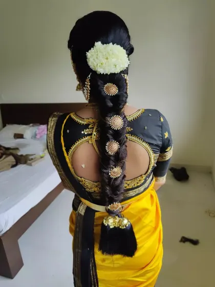 A traditional bubble braid look, with each section highlighted by a large gold disc, finished with a jasmine gajra.
