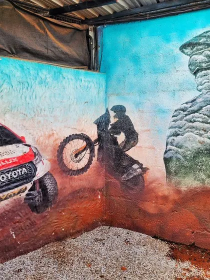 This corner of the Burnout Café mural features a rally car kicking up dust, a dirt bike in mid-air, and a ghosted image of a rider, capturing the different facets of off-road racing.