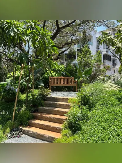 Stone steps lead up a small, grassy hill to a secluded wooden bench. This feature adds elevation and a sense of discovery to the garden, providing a quiet vantage point to overlook the landscape.