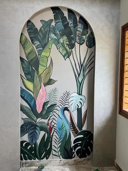 We love bringing the outdoors in. This tropical mural, framed by a beautiful archway, adds a burst of life and color to a hallway, making it feel like a lush paradise. The variety of leaves, including a pop of pink, creates a vibrant, layered look.