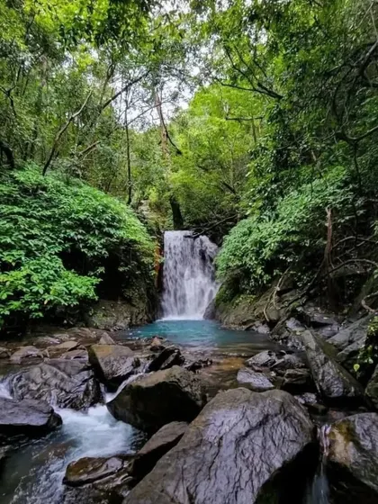 The beautiful turquoise pool at the base of an unexplored waterfall in Uttara Kannada, surrounded by lush greenery.