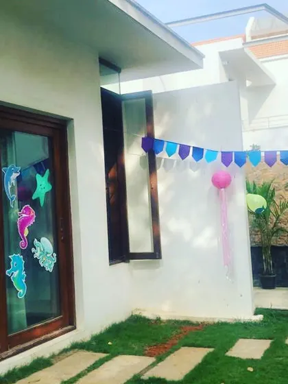 The party setup begins! Here you can see the outdoor space being decorated with blue and purple banners and sea creature cutouts on the windows, starting the transformation into an underwater wonderland.