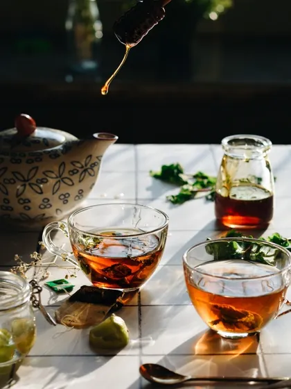 A beautiful, sunlit tea scene. The backlighting makes the tea and the honey drip glow, creating an almost magical effect. It’s a great example of using natural light to create drama.