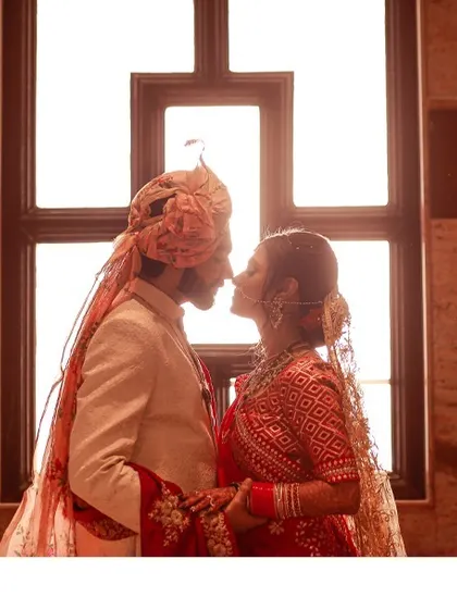 A romantic silhouette of the bride and groom against a window, their profiles almost touching, capturing a moment of pure intimacy.