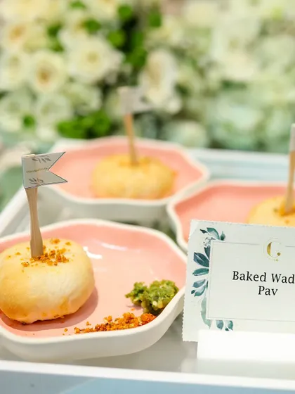 Our Baked Vada Pav, individually plated and garnished with a mini flag. This playful presentation elevates a beloved street food into a sophisticated appetizer for corporate events.