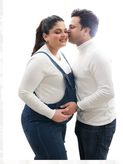 A sweet and gentle moment between expecting parents. This high-key studio shot with a clean white background emphasizes their connection.