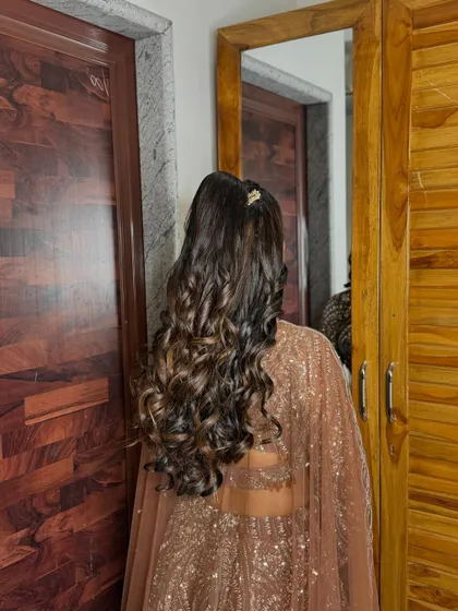 A back view of the hairstyle for the groom's sister. A high ponytail with voluminous curls is a great choice for a sangeet night.