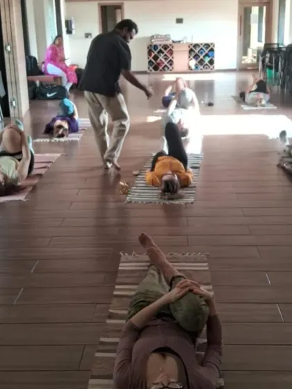 An instructor offers personalized correction on alignment during a group class. We prioritize safe and effective practice by ensuring each student understands the mechanics of the asana for their own body.