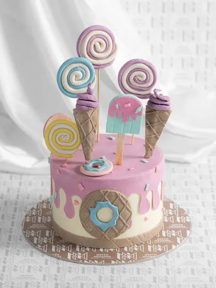 A candyland dream. This cake is dripping with sweetness, topped with fondant ice cream cones, lollipops, and donuts.
