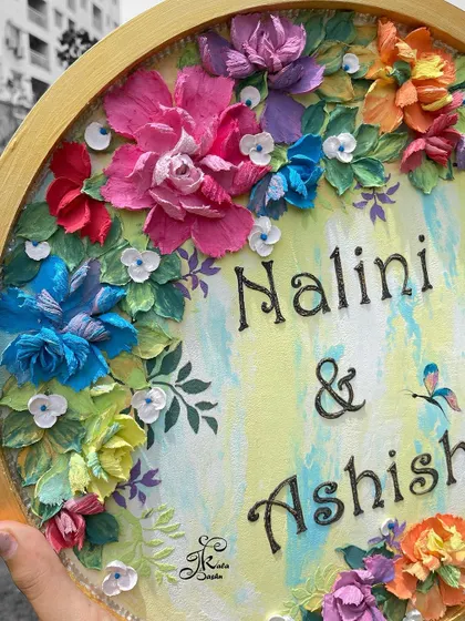 A close-up of the "Nalini & Ashish" nameplate, showing the beautiful script and the tiny hummingbird detail.