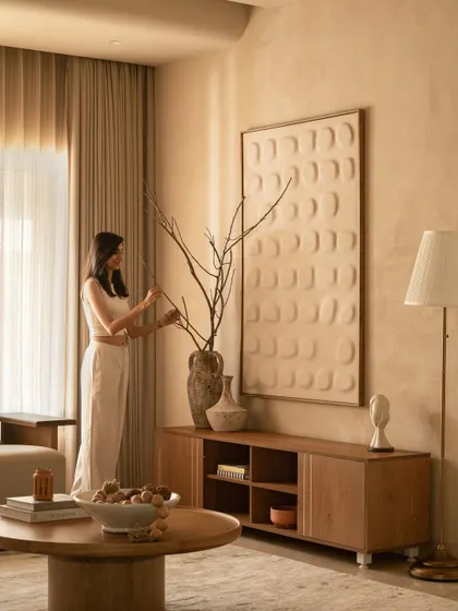 A moment of styling, arranging branches in a ceramic vase against a textured backdrop. This captures the essence of slow living, where every piece is chosen to tell a story.
