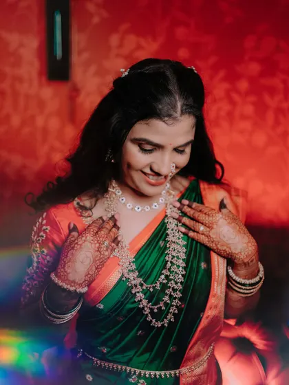 A lovely portrait of the bride in her green and orange saree. The soft, colorful light leak adds a dreamy and artistic touch to the photo, capturing her gentle smile.