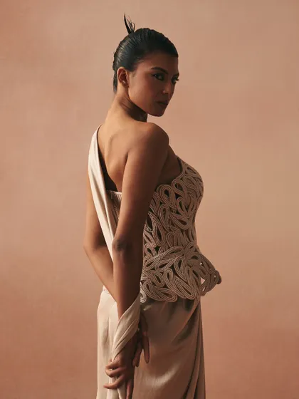 The Karov gown, where paisley rendered in zari cords on a cotton corset becomes the anchor. The satin drape skirt lets movement soften the garment’s sculpted intent.