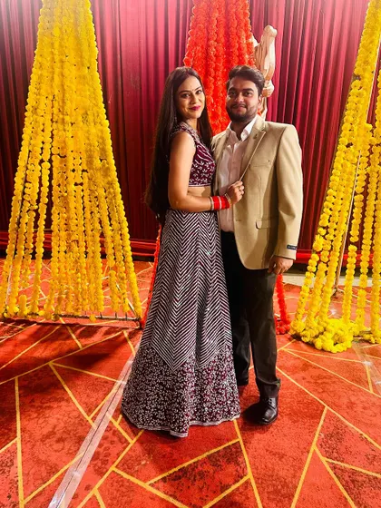A full-length shot of the couple against a festive backdrop of marigold flowers.