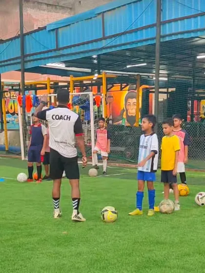 A coach addresses a group of young players, explaining the next drill. Clear communication and instruction are key to our coaching philosophy.