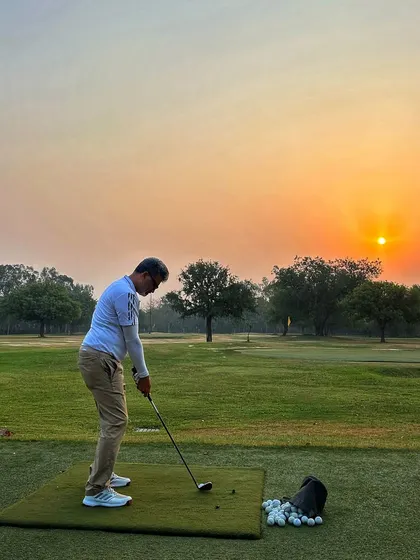 A lone golfer practices against the setting sun, a peaceful and beautiful end to the day.