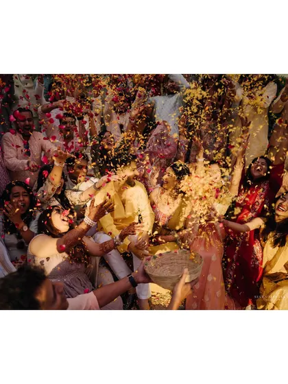 A shower of petals for the happy couple. This high-energy shot captures the excitement and love from family and friends during the Haldi ceremony.
