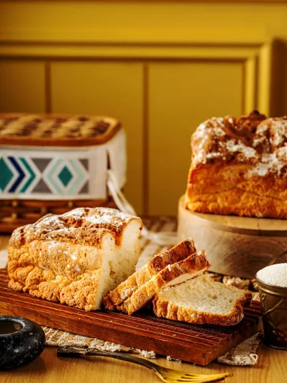 A rustic, artisanal loaf of bread, sliced to show its soft, airy crumb. Styled with a picnic basket and a dusting of flour, this image evokes a feeling of wholesome, homemade goodness.