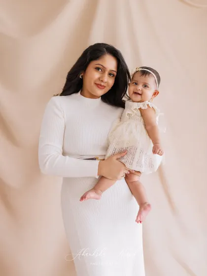 An elegant mother-daughter portrait. Their coordinated white outfits and the mother's loving hold create a sophisticated and heartfelt image.